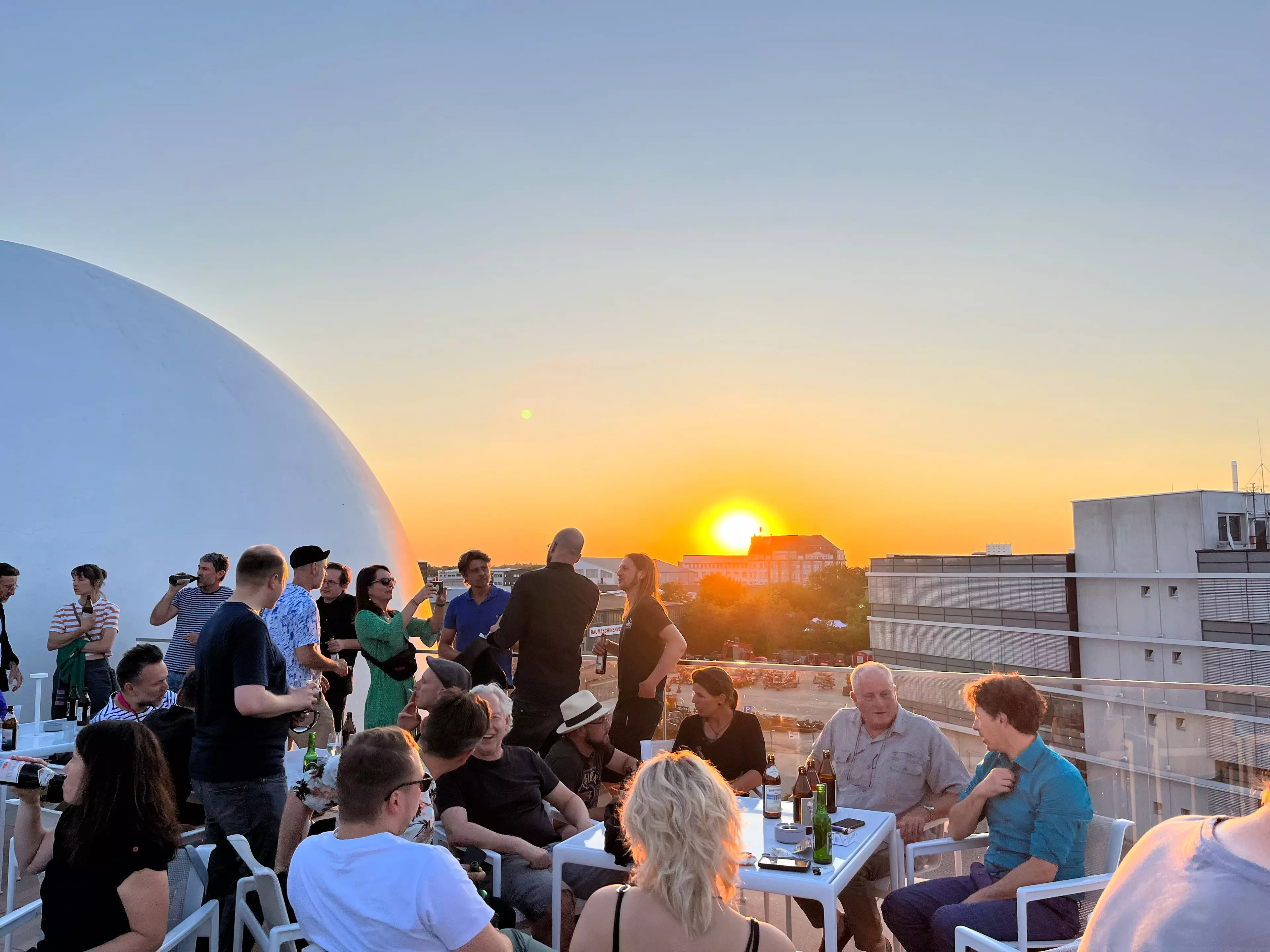 Menschen auf Terrasse bei Sonnenuntergang.