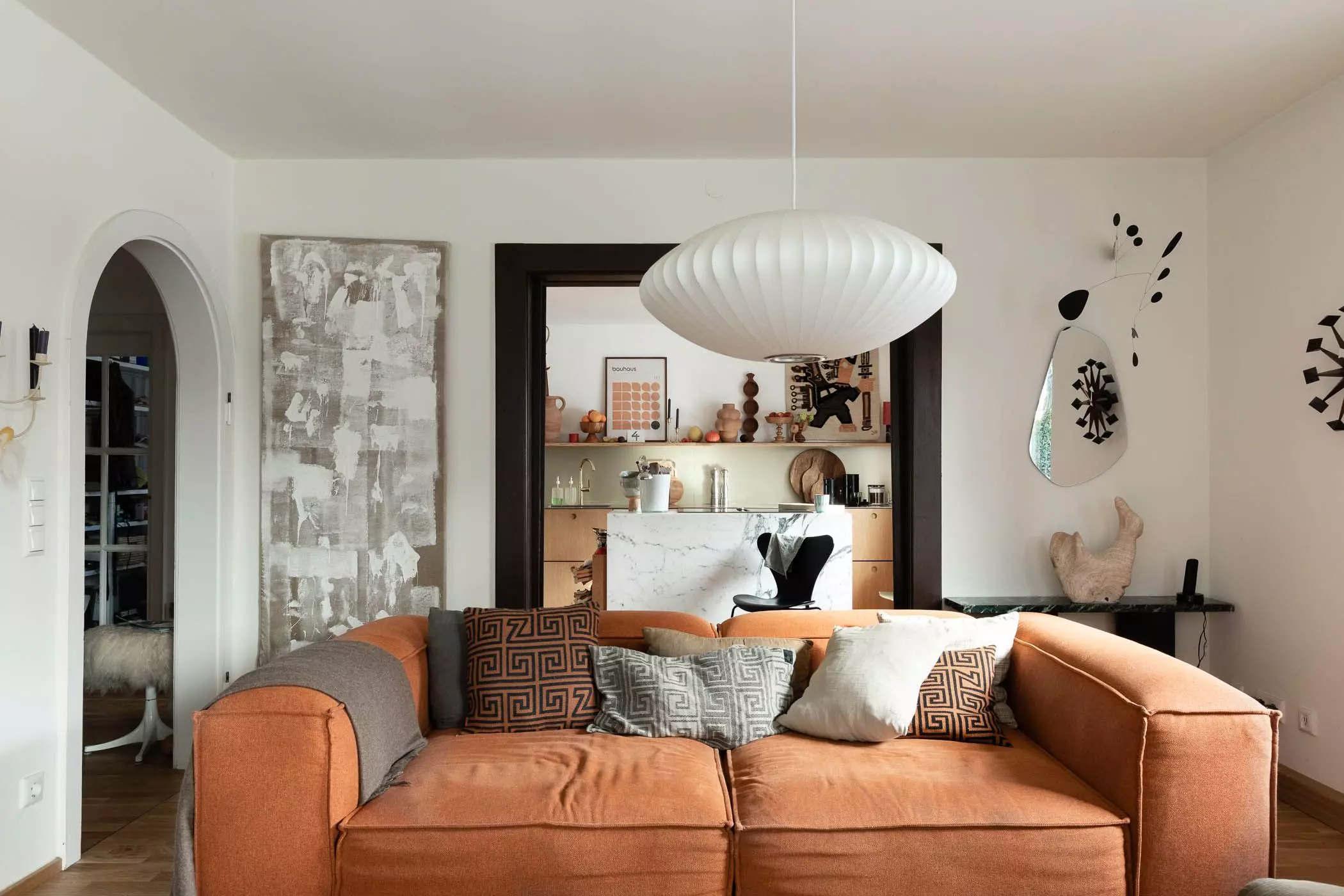 Wohnzimmer mit großem Sofa und offener Küche mit Marmor-Küchenblock - femtastics