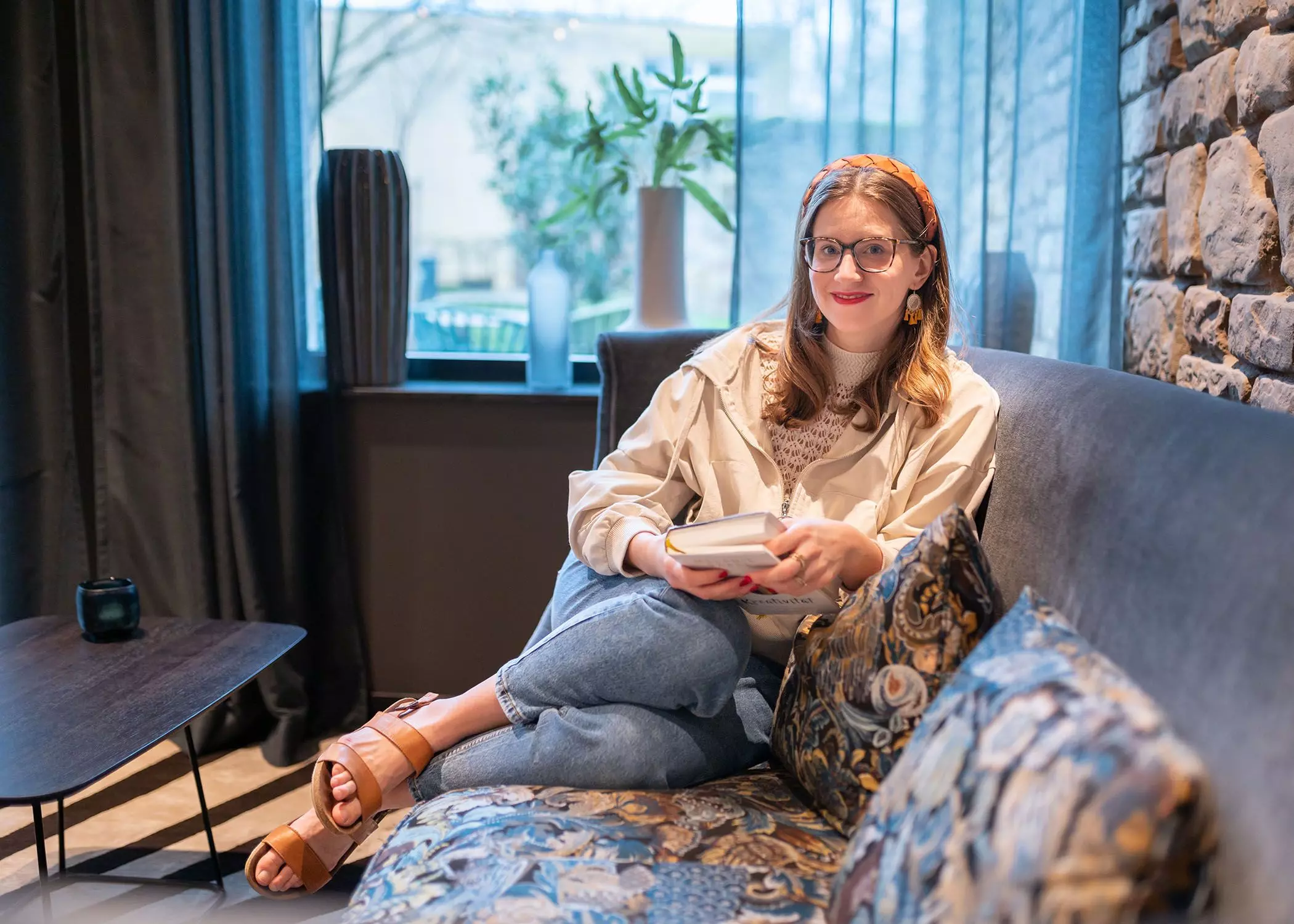 Autorin Corinna Mamok sitzt mit einem Buch auf dem Sofa | femtastics