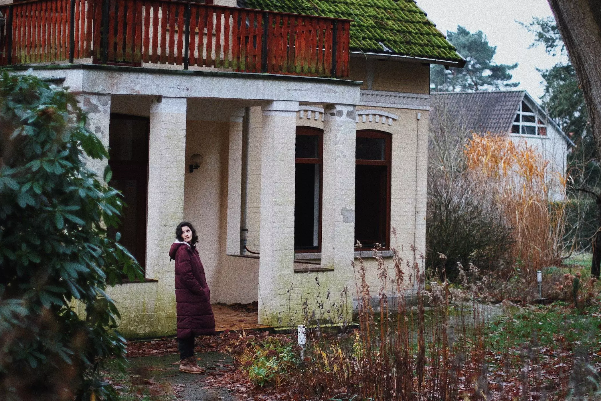 Büsra Qadir steht im Daunenmantel im winterlichen Garten ihrer Altbauvilla - femtastics