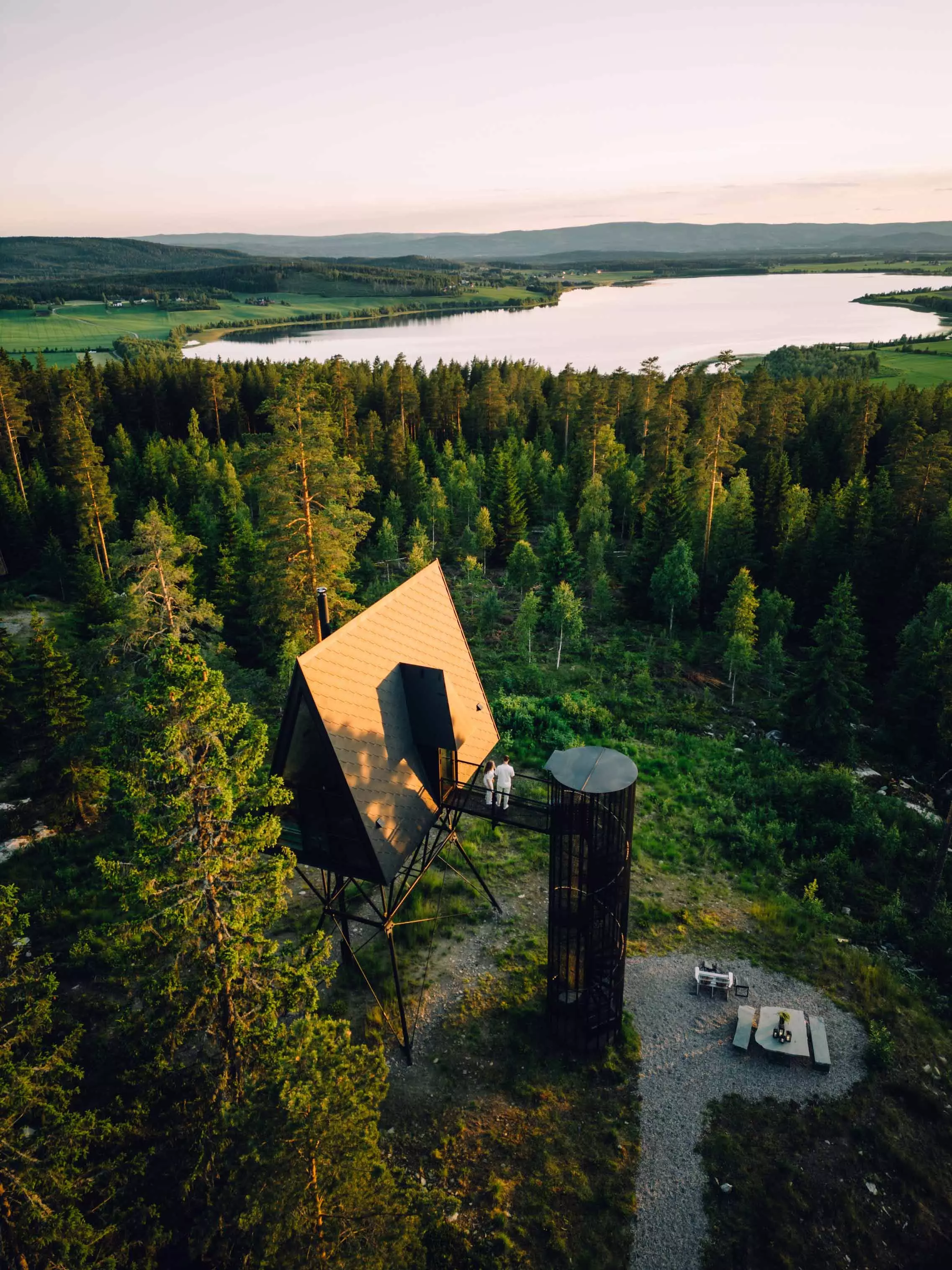 Preisgekroente PAN Cabin mit Spitzdach in Finnskogen, die auf ihren Stelzenbeinen ueber den Baumkronen zu schweben scheint.
