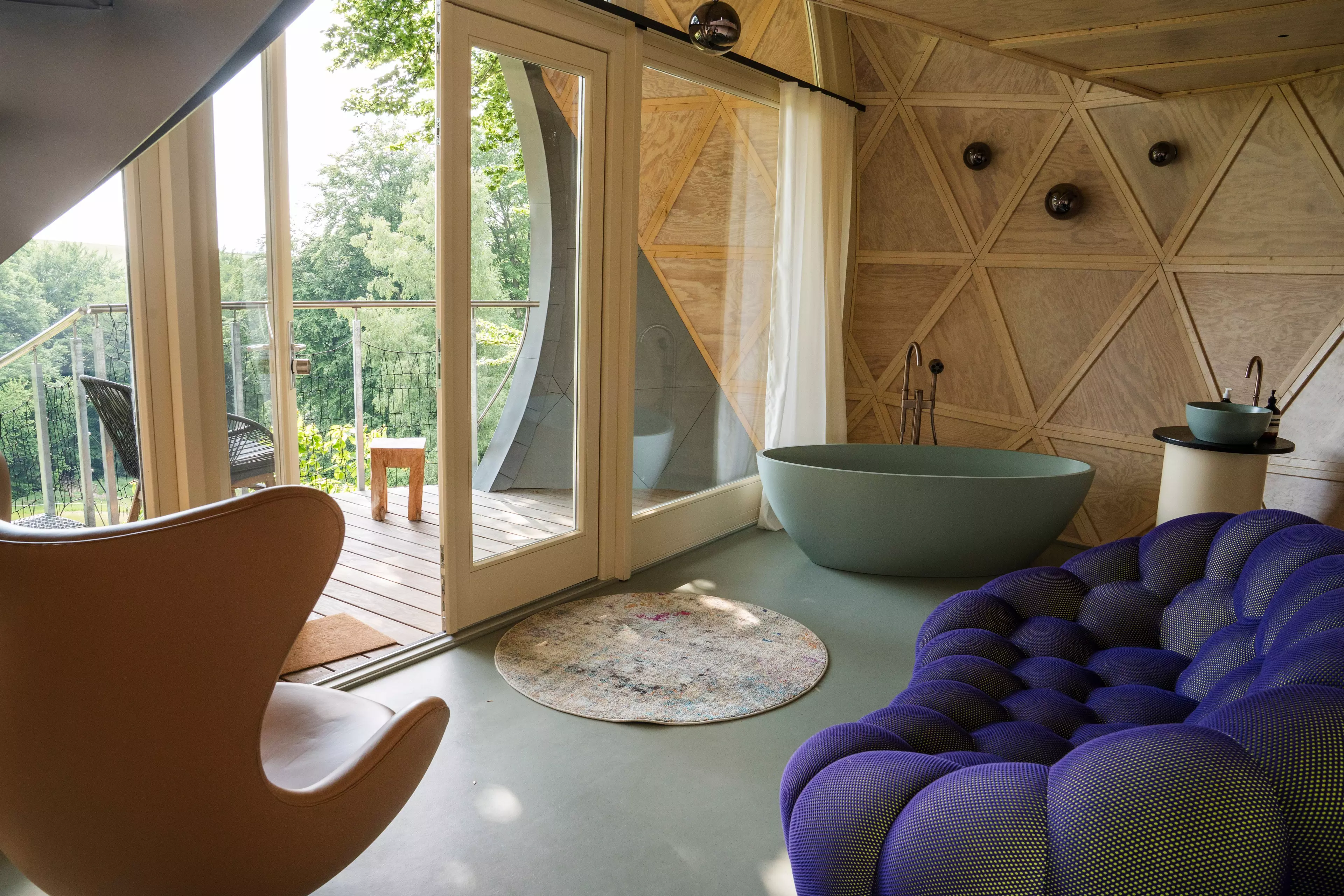 Badewanne, Sofa und Sessel: Innenausstattung eines K1-Baumhauses mit Hotelkomfort mitten im Wald.