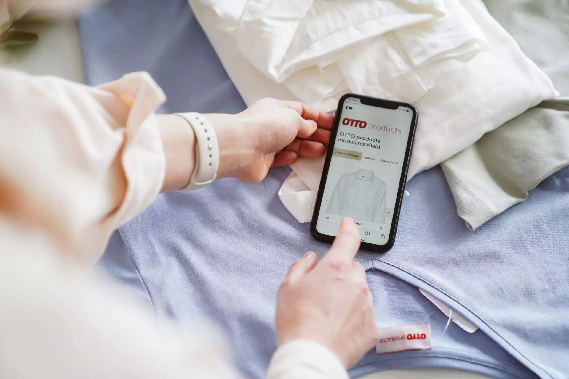 Frau scannt mit dem Smartphone einen NFC-Tag einer weißen Bluse von Otto - femtastics