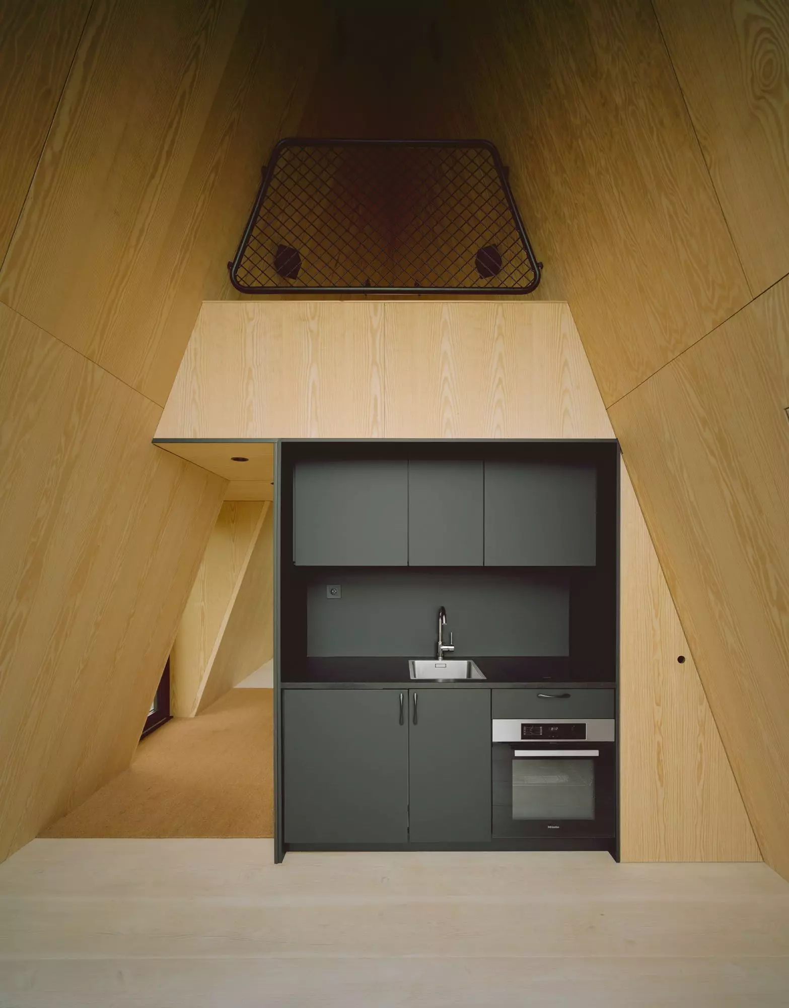 Innenraum einer PAN Cabin mit kleiner Einbaukueche und zweiter Schlafebene, bewusst ohne WLAN fuer echte Entschleunigung.