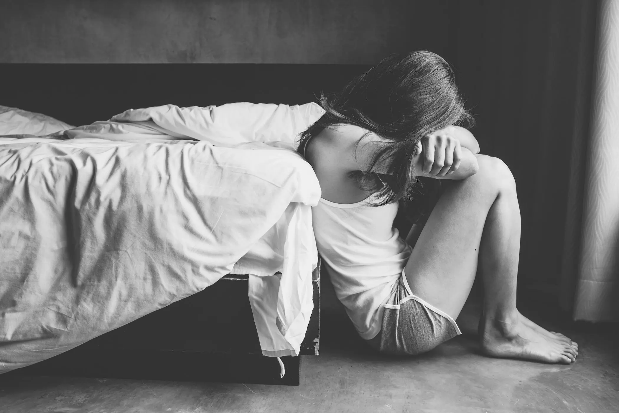 Portrait of depressed woman sitting alone on the floor in the bedroom.
