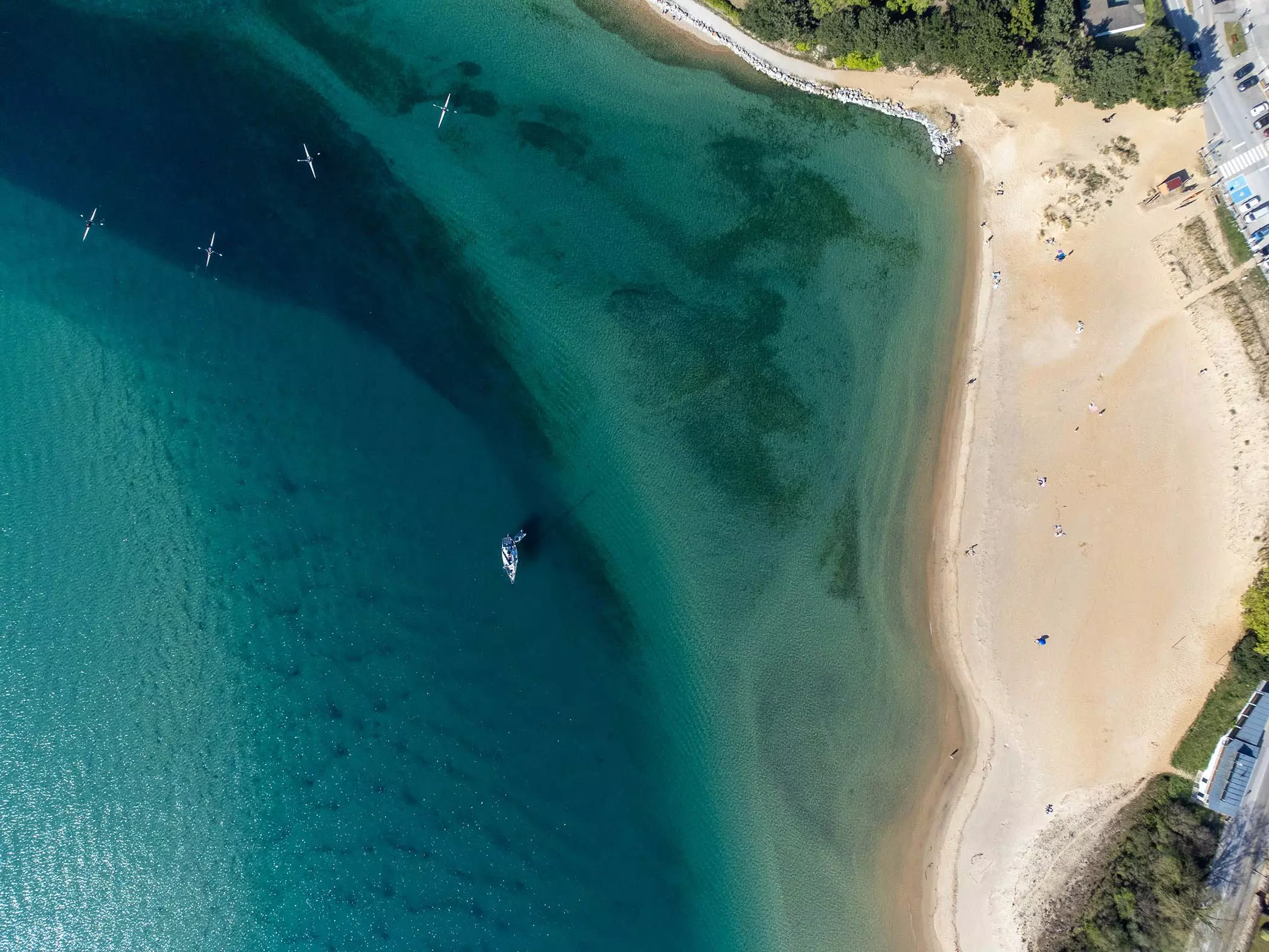 Segelboot und Kayaks vor Küste mit Sandstrand - femtastics