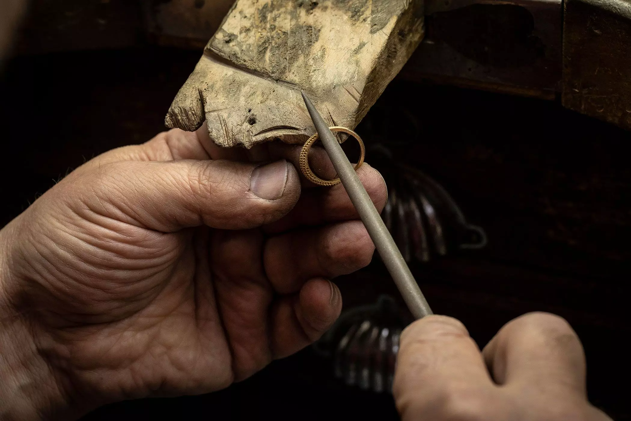 Hände, die mit einem Werkzeug an einem Goldring arbeiten – femtastics