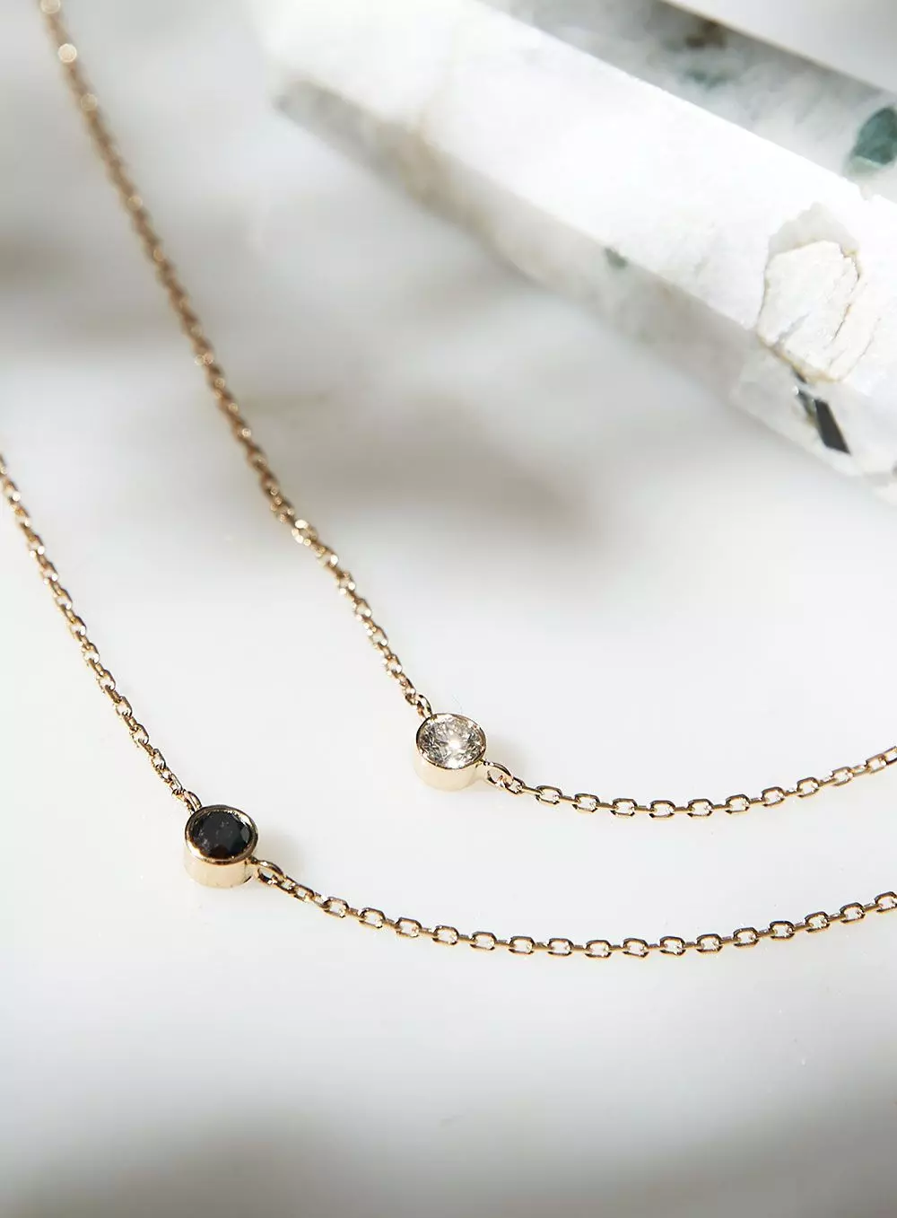 Zwei zarte Goldketten mit runden Diamanten in hell und schwarz – femtastics