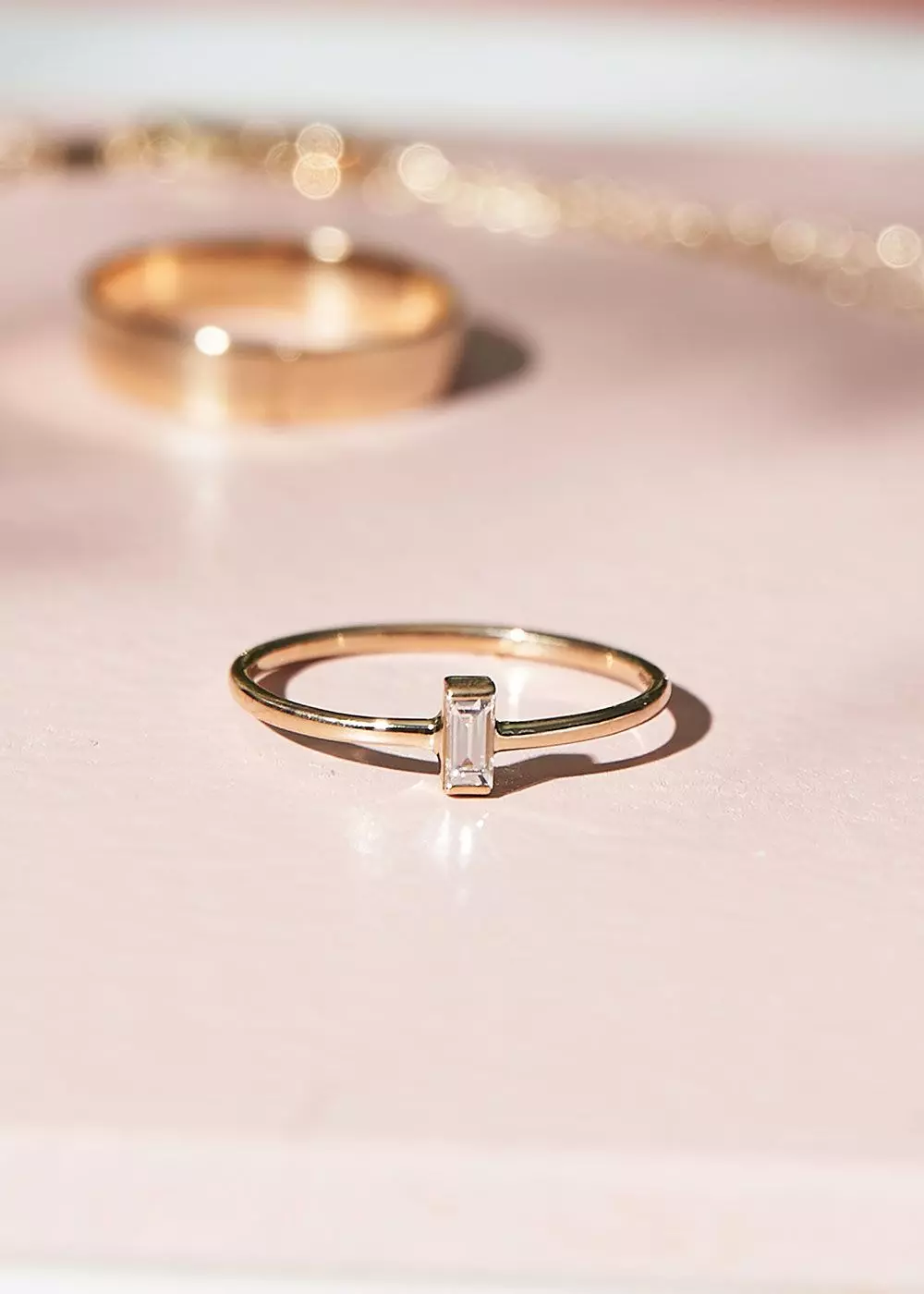 Goldring mit Diamant im Baguette-Schliff auf rosa Untergrund – femtastics
