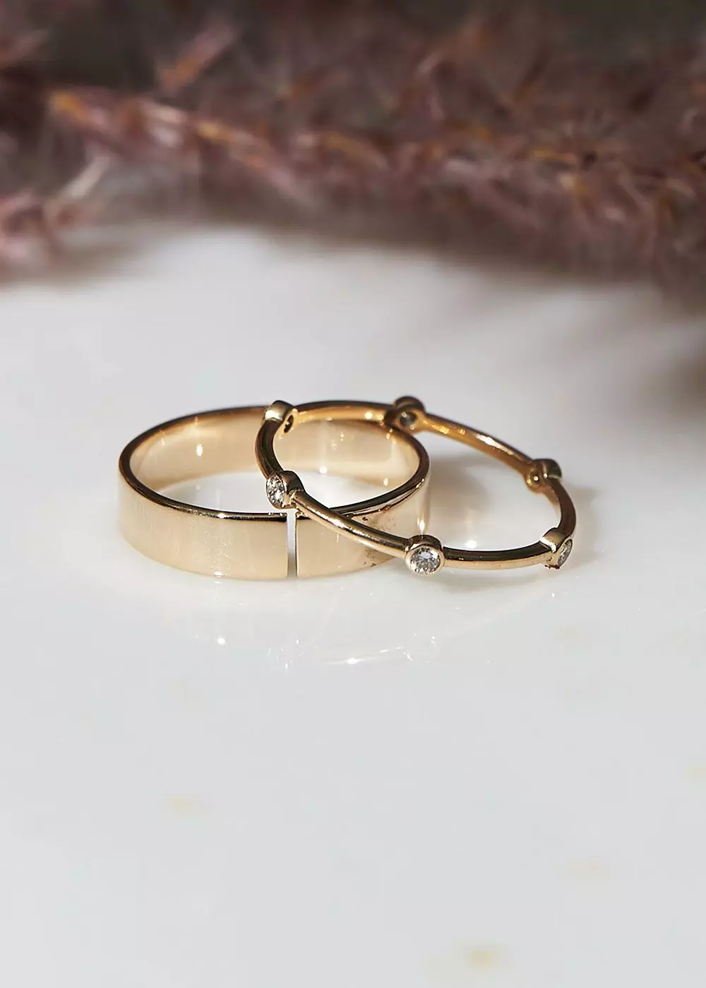 Zwei Goldringe – ein breiter und ein schmaler mit vielen kleinen Diamanten – auf weißem Untergrund – femtastics