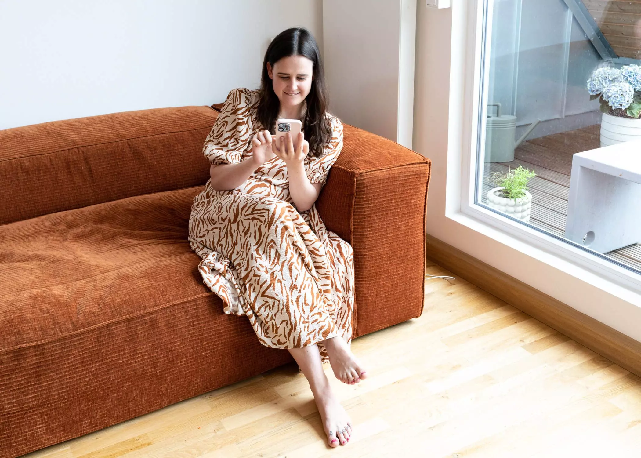 Julia Knörnschild sitzt mit Smartphone auf ihrem Sofa | femtastics