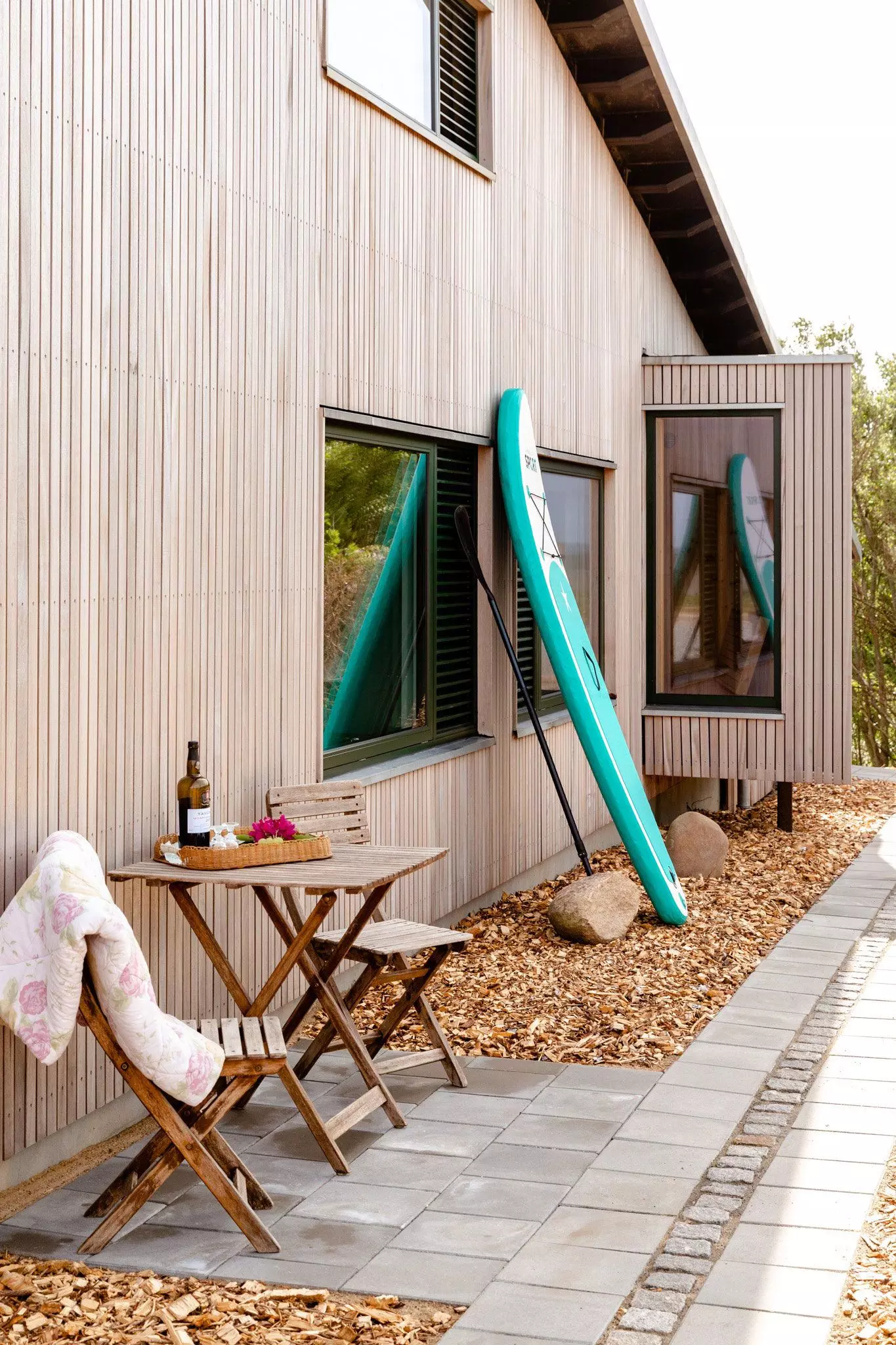 Tisch, Stühle und Surfbrett draußen an einem Ferienhaus – femtastics