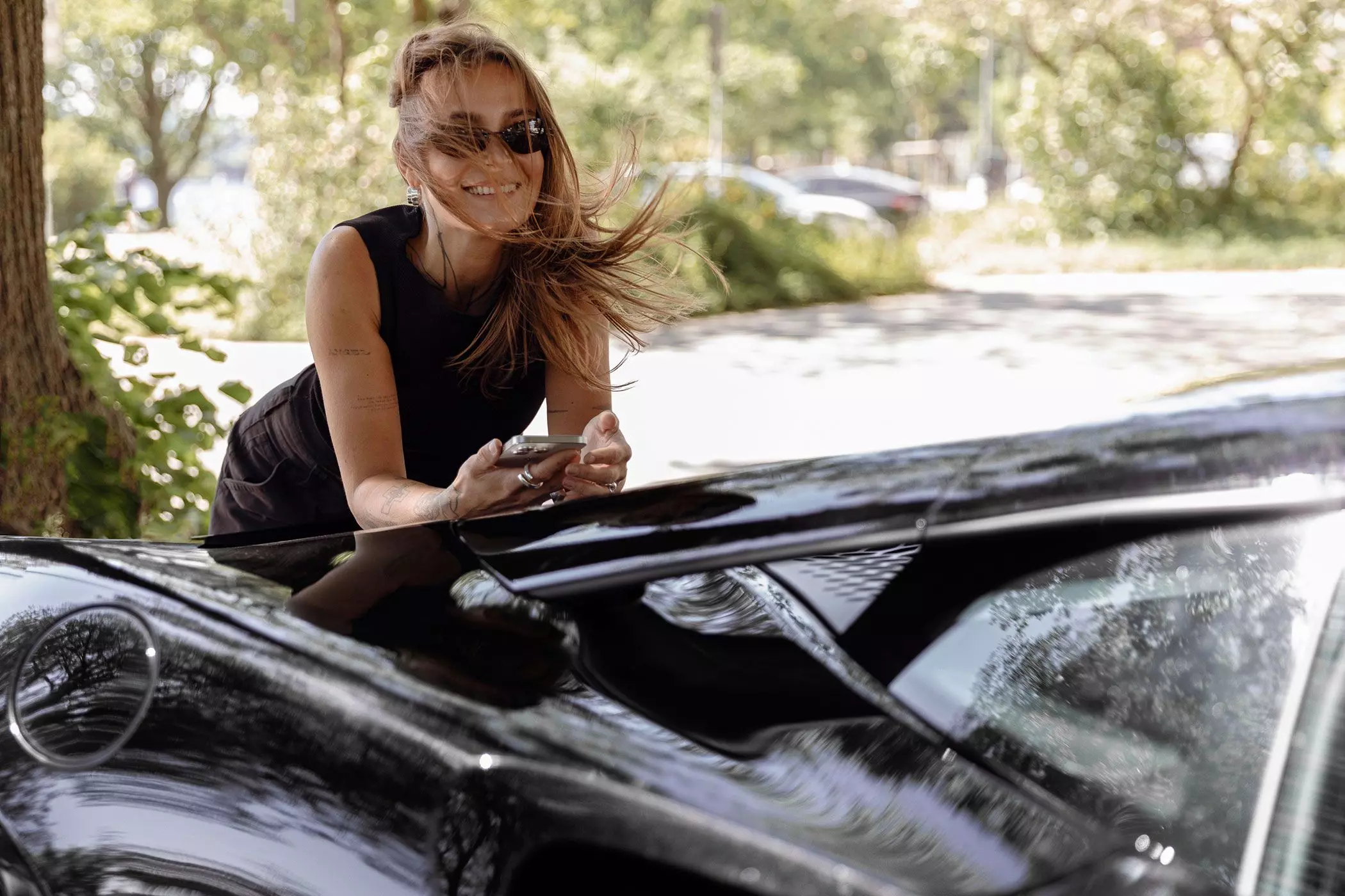 Melina Wendlandt mit Sonnenbrille auf dem Auto lehnend