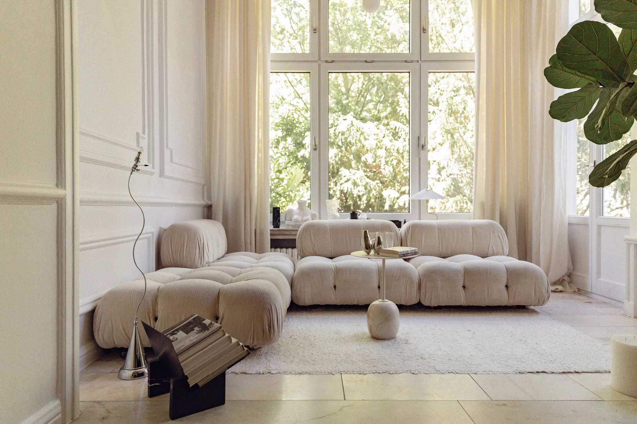 Altbauwohnzimmer mit beigem Sofa und großen Fenstern mit hellen Gardinen