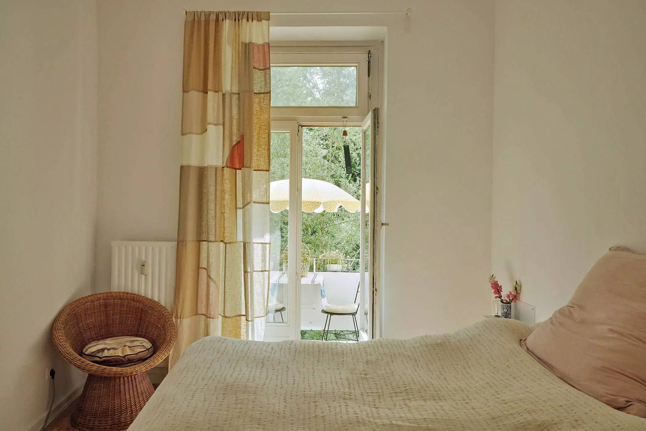 Blick durch ein Schlafzimmer auf einen Balkon mit gelbem Sonnenschirm - femtastics