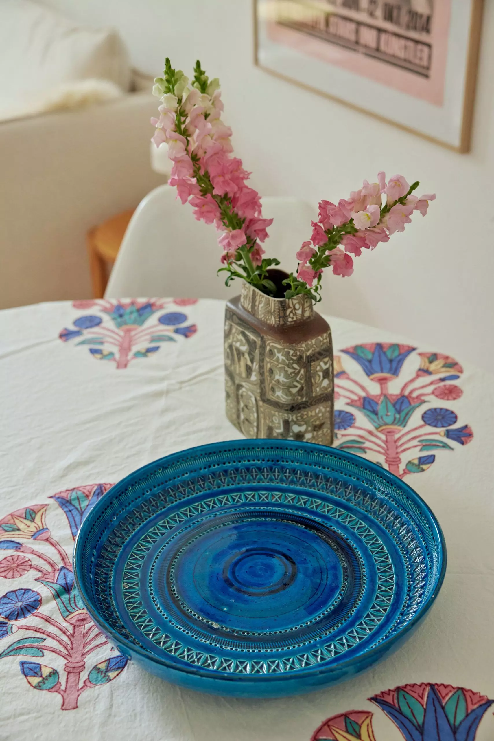 Blauer Keramikteller und Vase mit Blumen auf einer bunten Tischdecke - femtastics