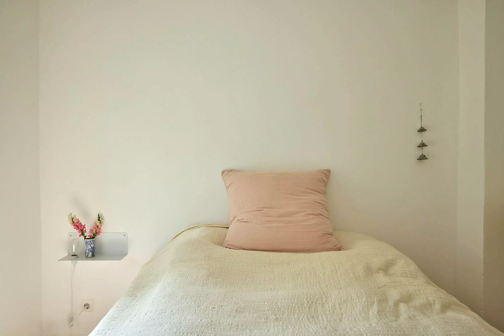 Bett mit rosa Kissen, kleinem Wandregal links und Wandmobile rechts davon - femtastics