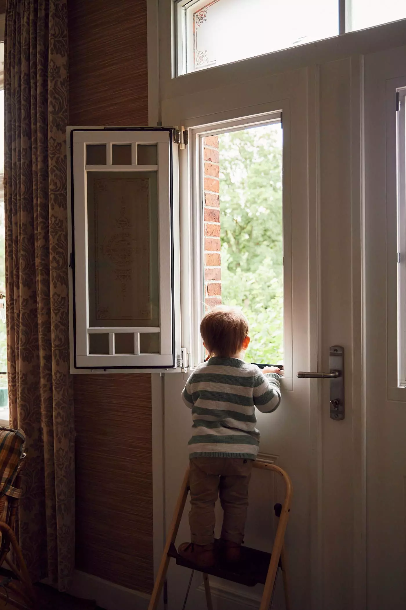 Kleiner Junge schaut im Bauernhaus aus dem Fenster - femtastics