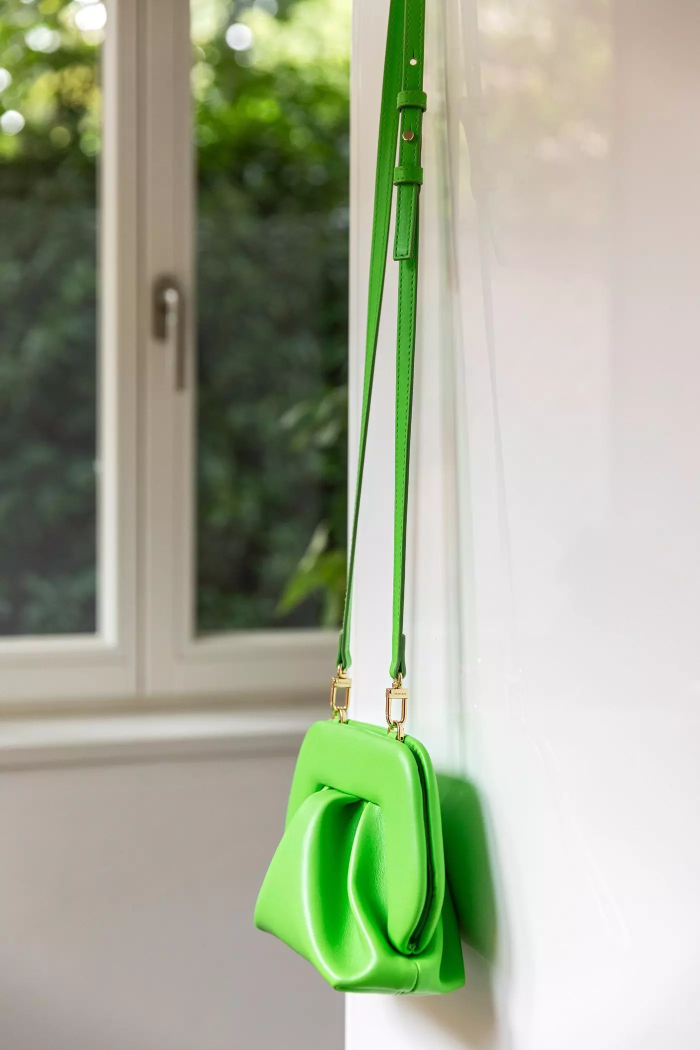 Neongrüne Handtasche hängt an weißer Tür - femtastics