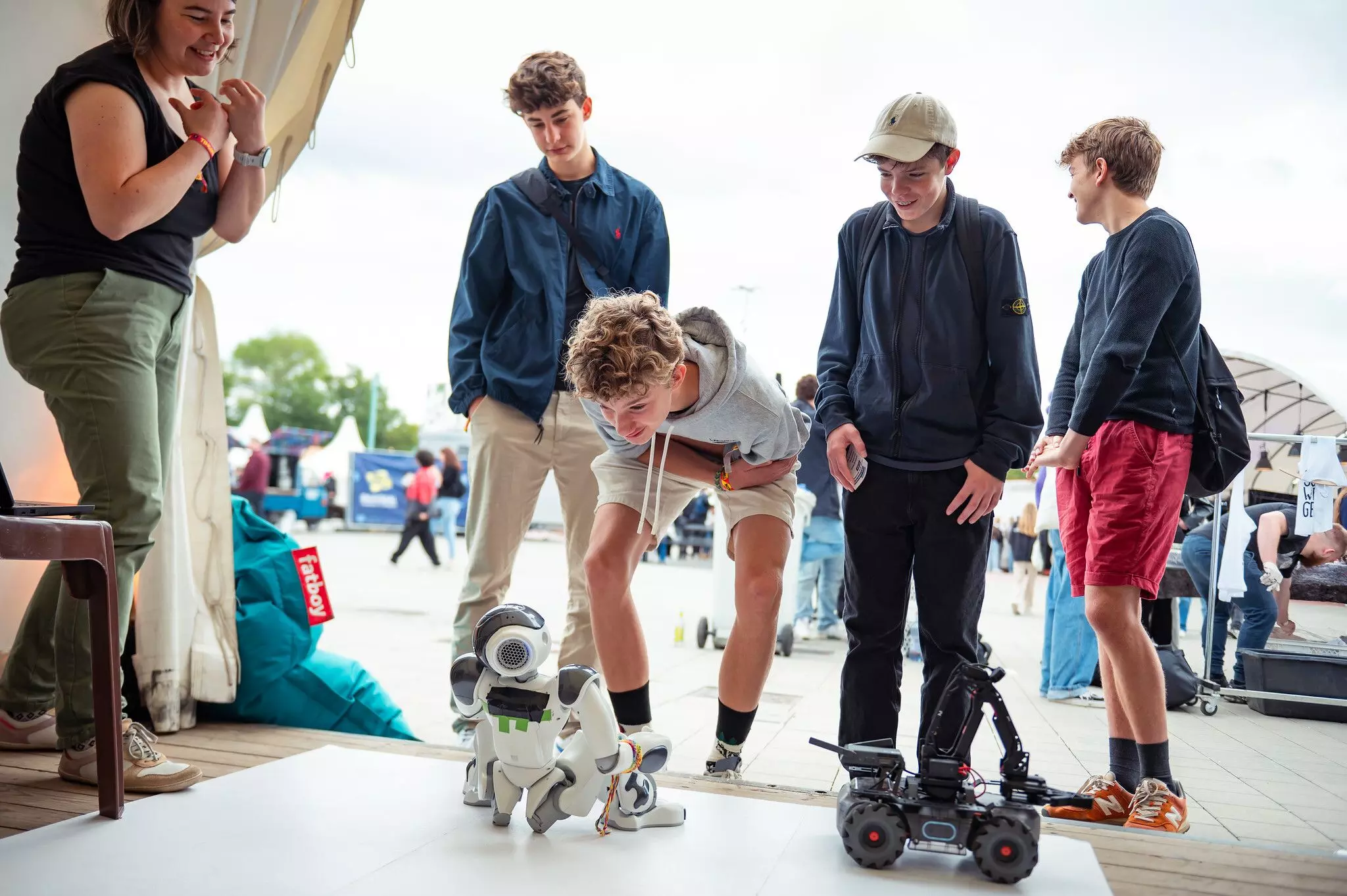 Jugendliche stehen um einen Hunderoboter herum