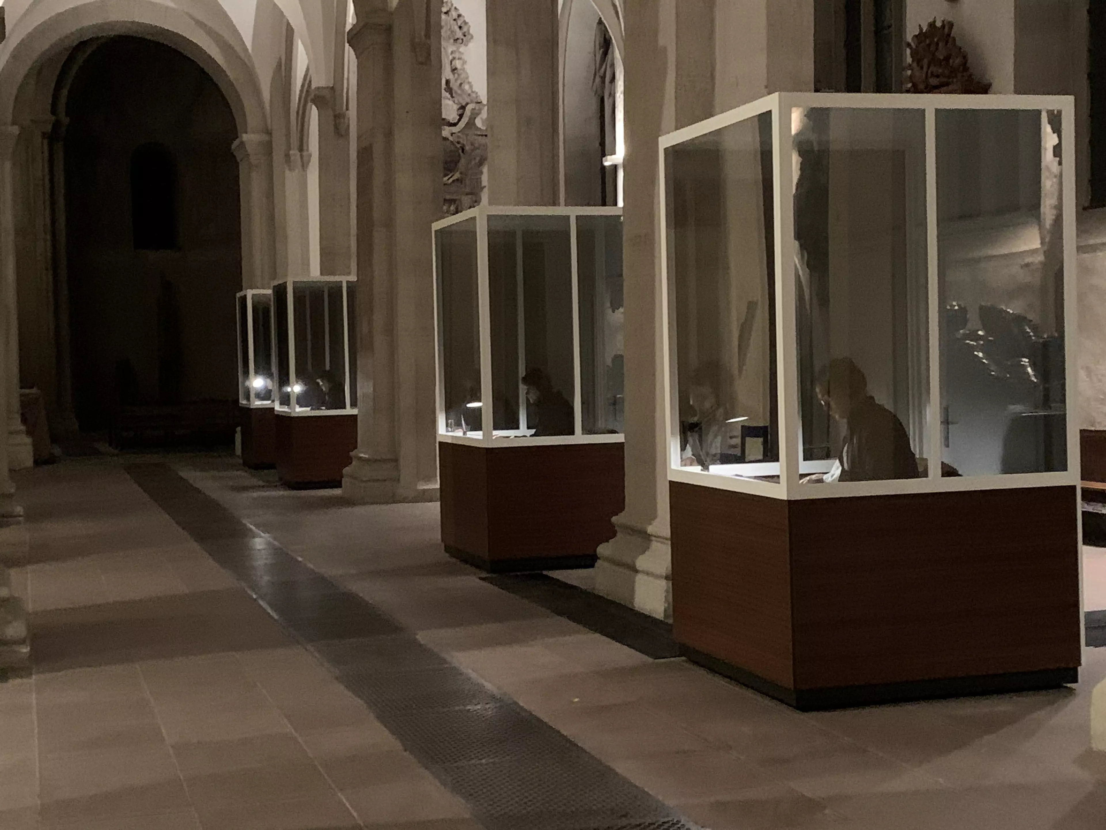 Der Innenraum einer Kirche. Hier stehen vier Kabinen, in denen Menschen sitzen und lesen.