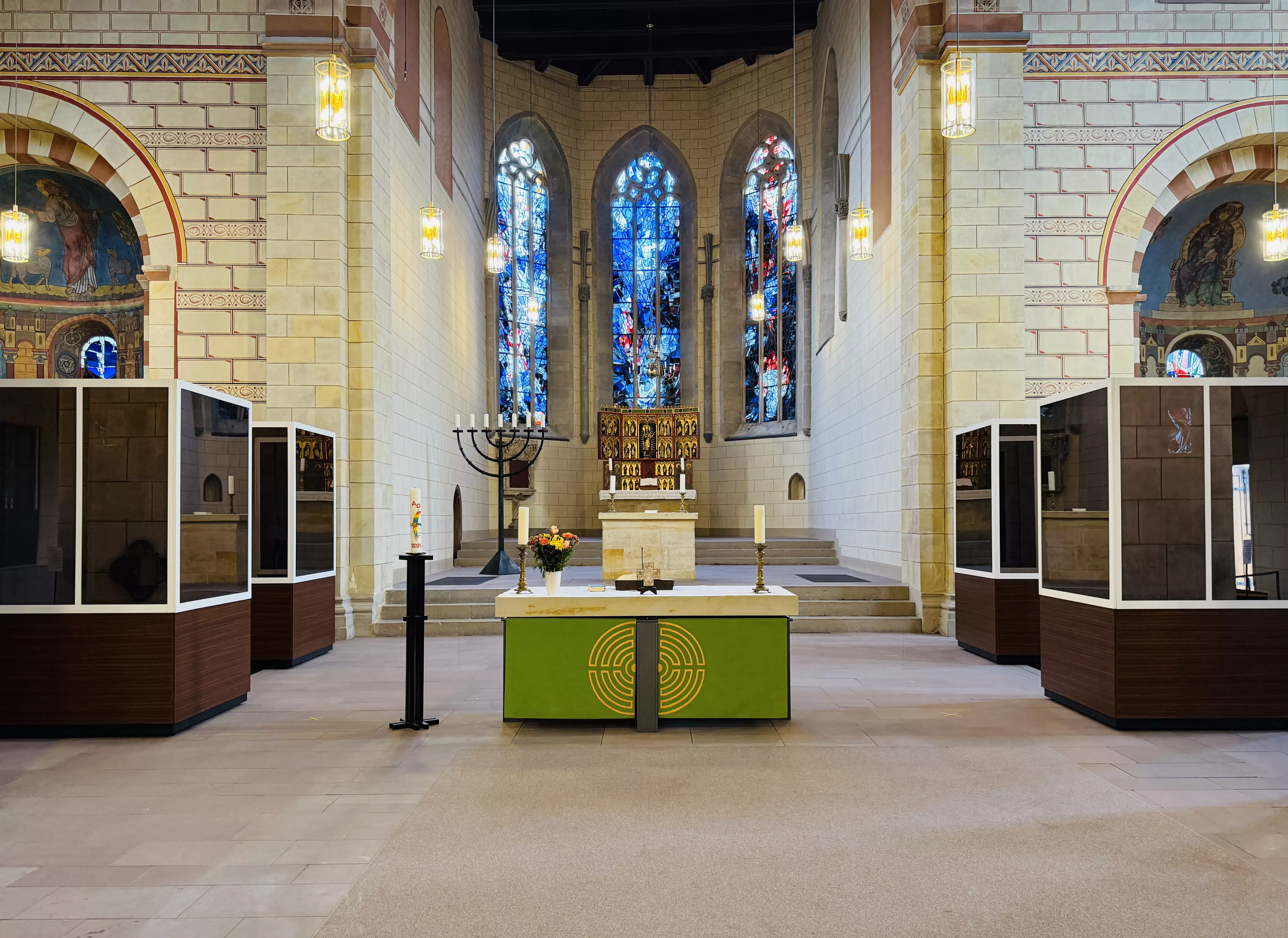Der Innenraum der Klosterkirche St. Marienberg in Helmstedt. Blick in Richtung des Altars. Links und rechts neben dem Altar stehen jeweils zwei verspiegelte Glaskabinen. Der Innenraum der Kirche spiegelt sich in ihnen. Geradeaus der Blick auf die bunten Kirchenfenster.