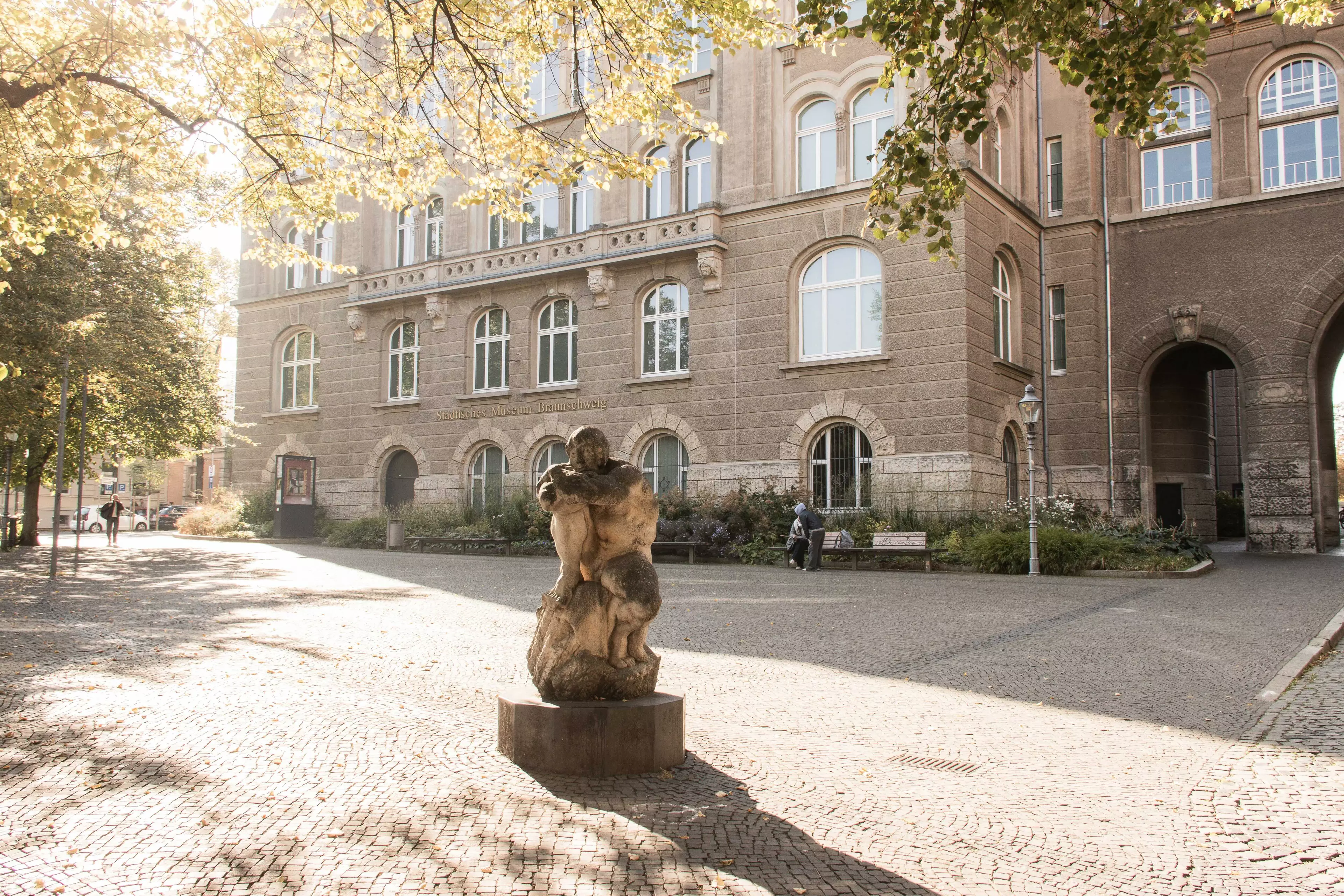 Der Platz vor dem Städtischen Museum in Braunschweig. Im Vordergrund ist eine Skulptur des Künstlers Jürgen Weber zu sehen, die den Titel „Die große Verweigerung“ trägt. Sie soll eine trotzige Selbstdarstellung des Künstlers als Herkules, der den Kampf mit seinen Kritikern führt, zeigen.